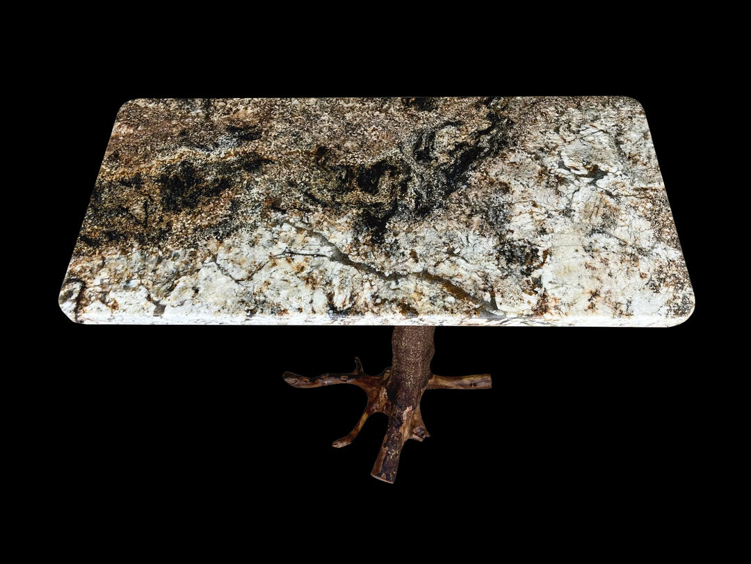 Top view of a magma gold granite top with a brown tree stump base against a black back drop.