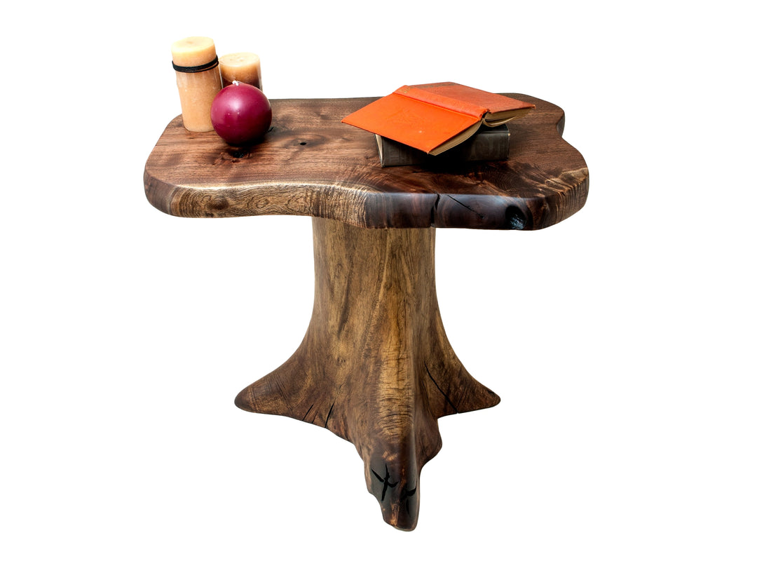 Staged Black Walnut side table with books and candles on a live edge top with a white background.