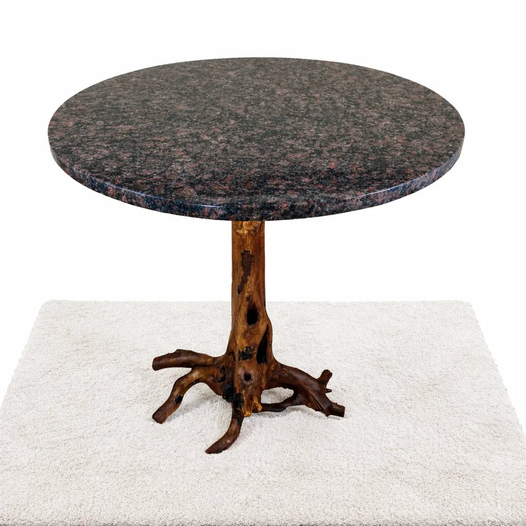 Top view of a round Blue Dunes granite top table supported by a tree root base with a white background.