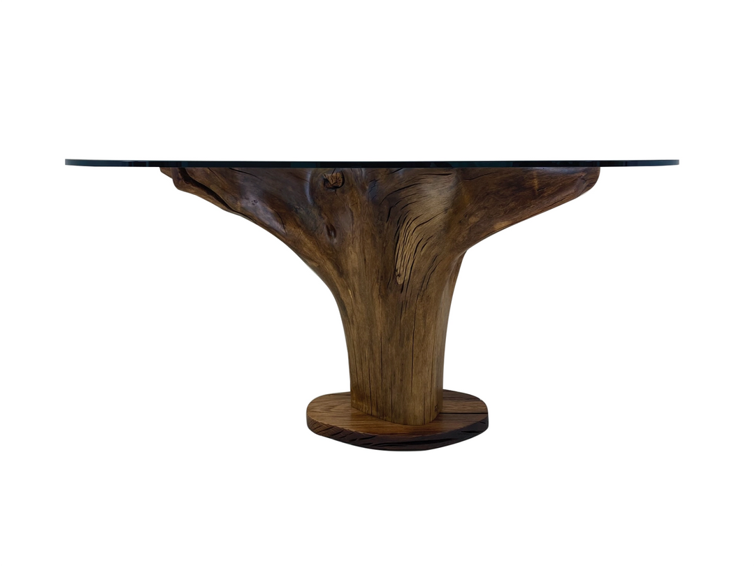An oak tree stump dining table with roots up and supporting a large glass top.