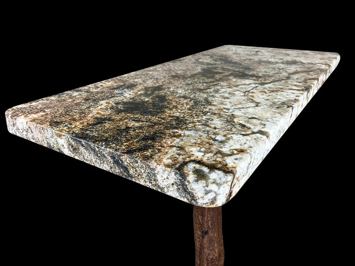 Close up angled view of a rectangular magma gold granite top of a console table on a tree base.
