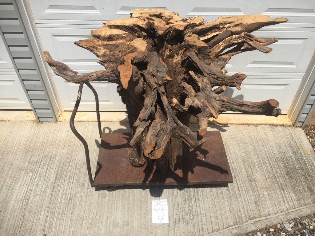 A large weathered and unfinished tree stump on a metal cart with a garage door in the background.