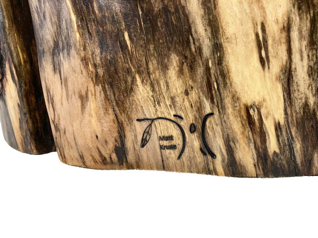 Brand logo of Matt Kruse on the base of a wood log side table.