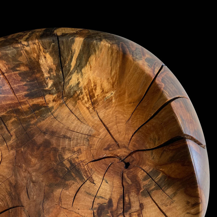 Close-up of seat area of a solid sycamore chair showing grain patters and natural oil finish.  Black background.
