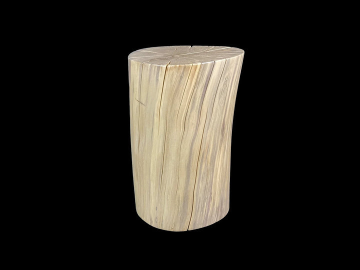A cylindrical wooden side table made from a natural wood log, featuring prominent grain patterns in light beige and cream tones, set against a solid black background.