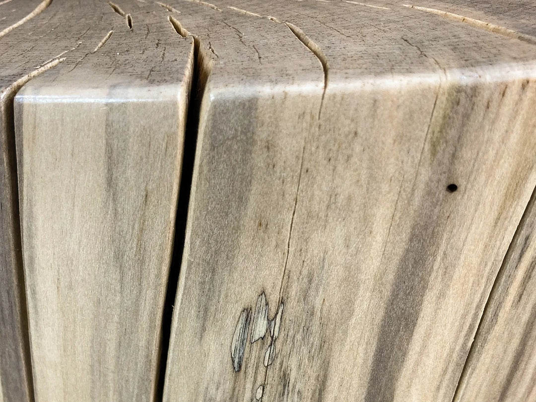 Close-up of a light natural wood surface of a log side table with visible grain, knots, and a vertical sanded split.