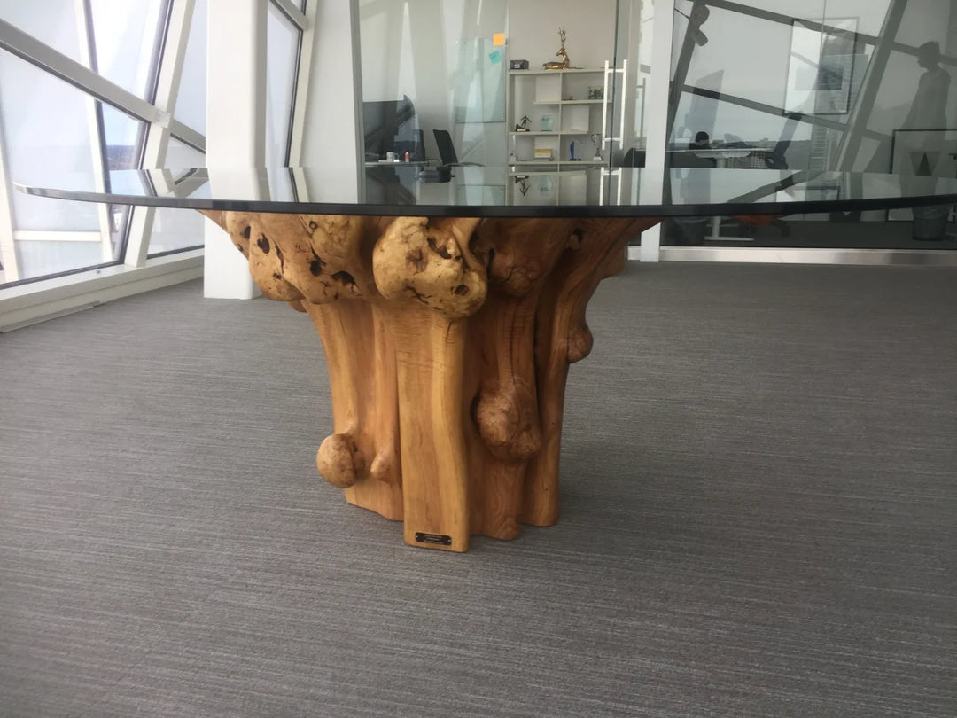 A large tan colored Black Locust  Conference table in a high rise office surrounded by glass windows overlooking a city.