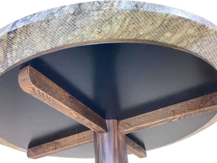 Under carriage of dining table support for granite top.  Large black disc with stained veneer edge supported by oak joists.  Granite overhangs by 3"