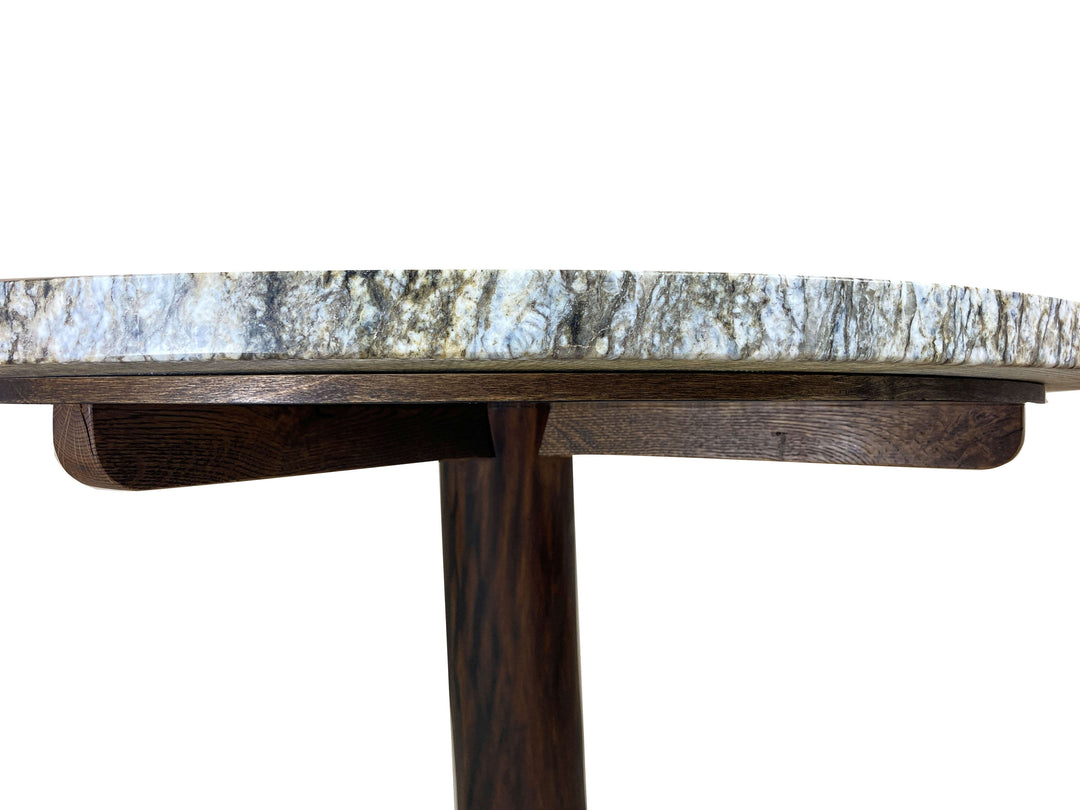 Round support disc with wood veneer on oak joists stained dark brown.  Round granite top mounted above with a white background