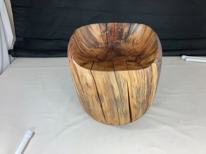 Video of a hand carved solid Sycamore chair in shape of an egg with a black canvass backdrop and white floor.